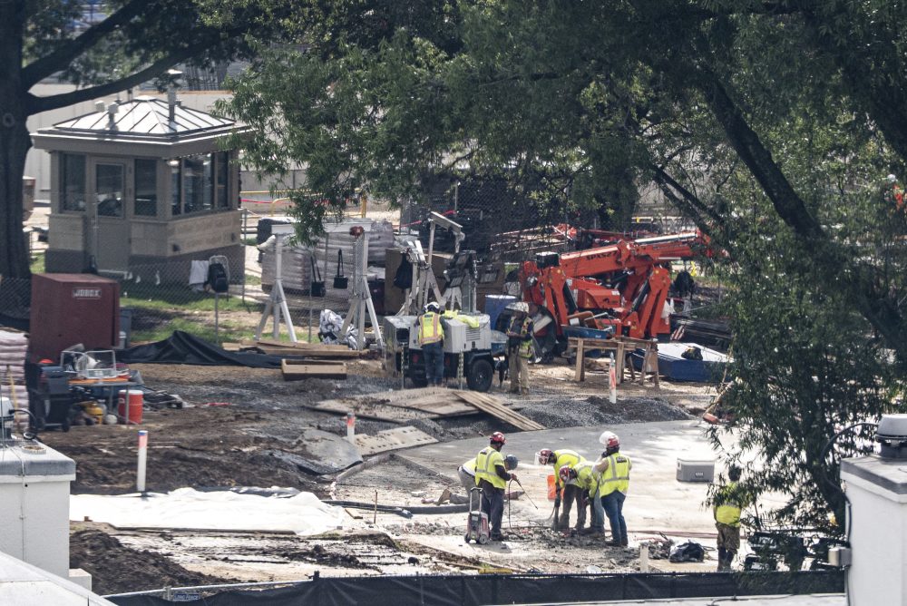 Crews remove the granite seal on the White House helipad, signaling potential project delays